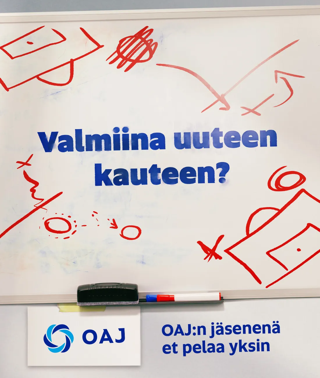 Seinällä oleva valkotaulu ja tusseja. Taulussa on joukkuepelien taktiikkataulun kaltaisia kuvioita ja teksti: OAJ:n jäsenenä et pelaa yksin